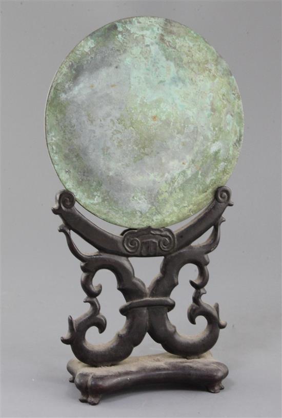 A Chinese bronze circular mirror, Han dynasty or later 18cm diameter, wood stand